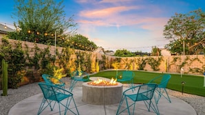 An outdoor patio with a fire pit, four chairs, and a well-maintained lawn. - Golfer`s Delight | Pool Club House + BBQ Island (Indio)