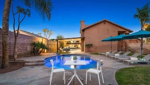 A backyard with a swimming pool, a patio table, and lounge chairs. - Golfer`s Delight | Pool Club House + BBQ Island (Indio)