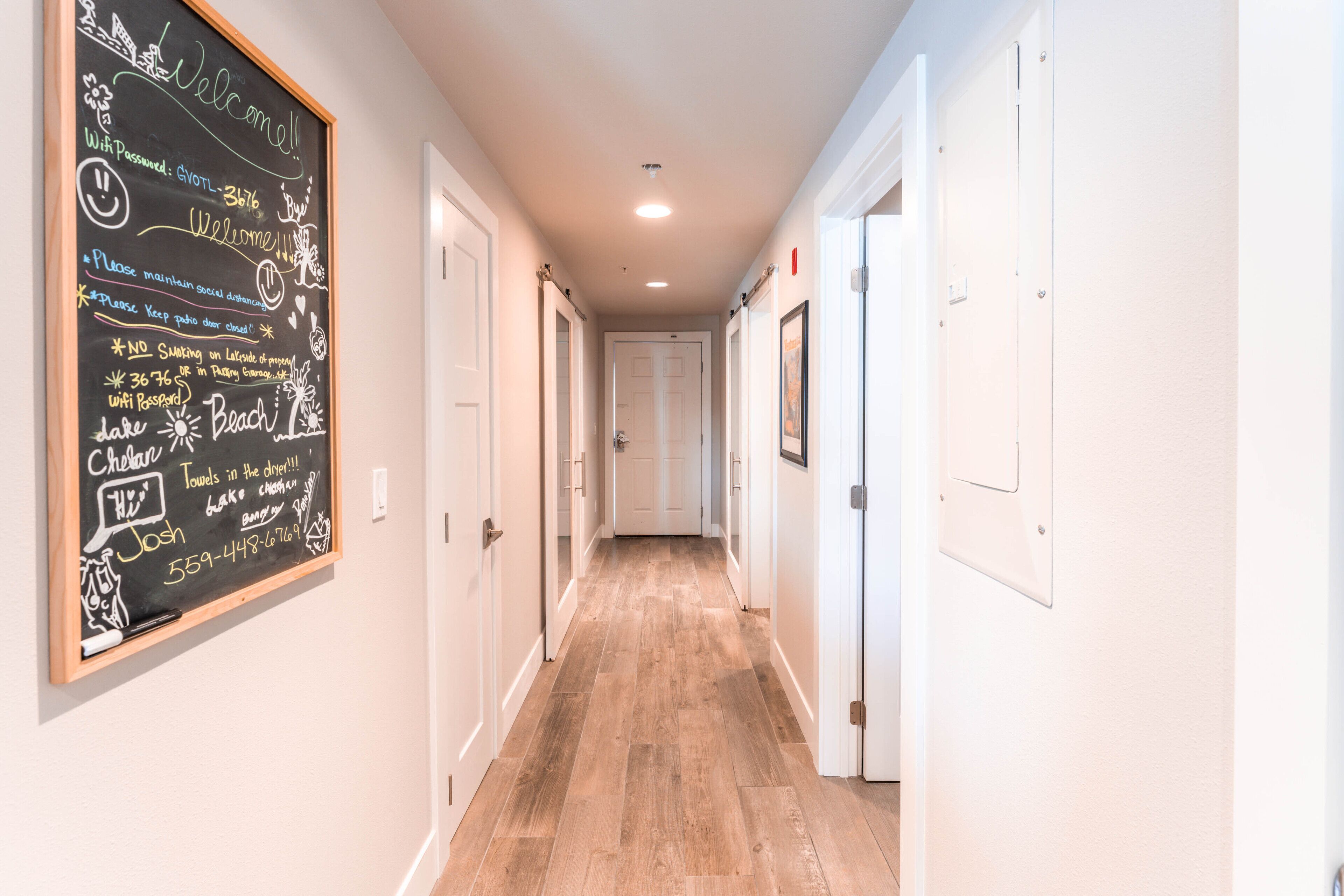 A hallway with a chalkboard displaying various messages and a contact number.