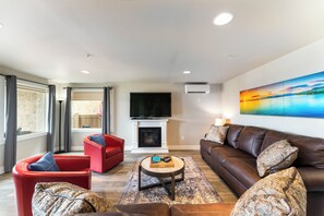 A living room with a fireplace, red and brown leather sofas, a coffee table, and a large painting on the wall.