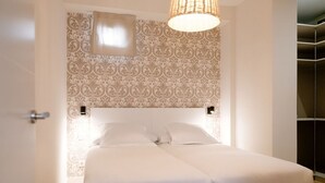 A bedroom with a large bed, patterned wallpaper, and a hanging light fixture. - Apartamento Premium 2 Dormitorios 1 Baño con Balcón (Madrid)