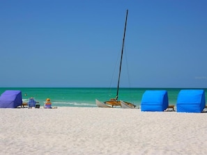 A beach with a sailboat, covered chairs, and a tent. - Bayview Getaway!  Sarasota FL (Sarasota)