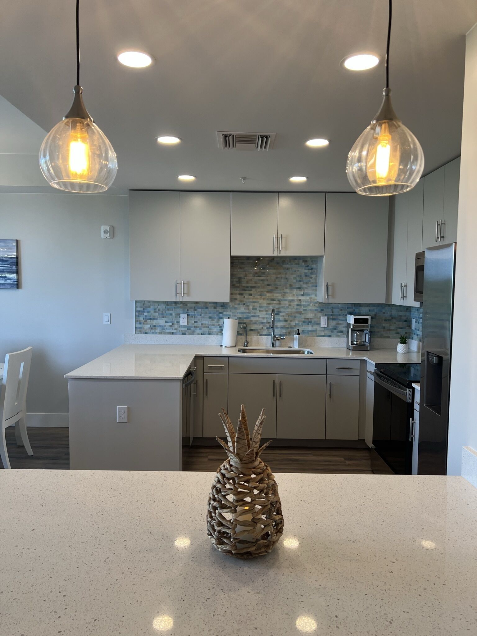 A modern kitchen with two pendant lights, a central island, and a backsplash.
