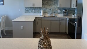 A modern kitchen with two pendant lights, a central island, and a backsplash.