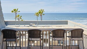 A terrace with a view of the ocean, featuring a table and four wicker chairs. - Top Floor Panoramic Whitewater Ocean Views in Oceanside! 1,081 Sq Ft (Oceanside)