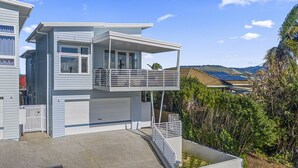 Uma casa moderna de dois andares com varanda, garagem e entrada pavimentada.