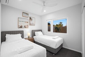 A bedroom with two beds, a ceiling fan, and a window with a view of the outdoors. - Bluehaven Woolgoolga (Woolgoolga)