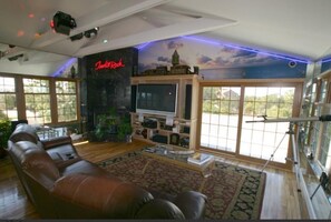 Relax in this stylish living room with a large sofa, flat-screen TV, and cityscape mural on the ceiling.