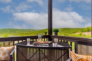 Un espace extérieur aménagé, abrité et doté d’une table pour deux, offrant une vue sur un paysage verdoyant et luxuriant.