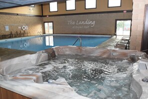 Une piscine avec un jacuzzi au premier plan, une enseigne indiquant « The Landing at Eagle’s Nest », et une vue sur l’extérieur à travers une fenêtre.