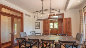 Un comedor con una gran mesa de madera, seis sillas y una lámpara colgante.