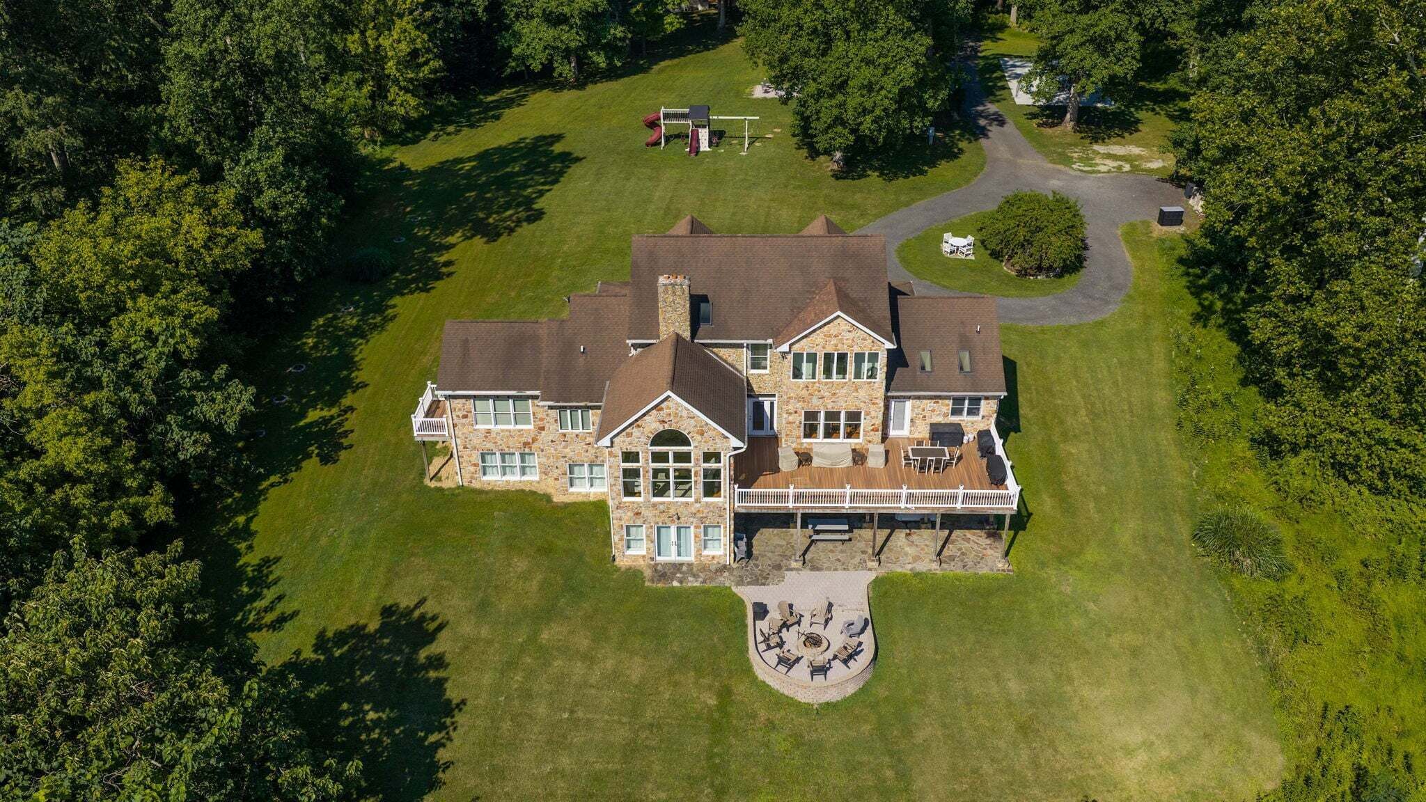 Une grande maison en pierre dotée d’une terrasse et d’un espace salon extérieur.