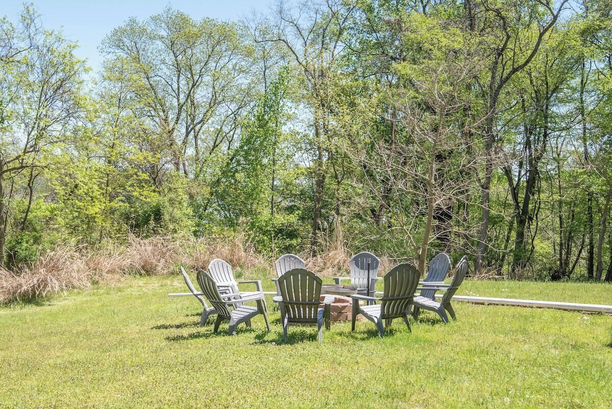 Un espace extérieur verdoyant, avec des fauteuils Adirondack et une table ronde.
