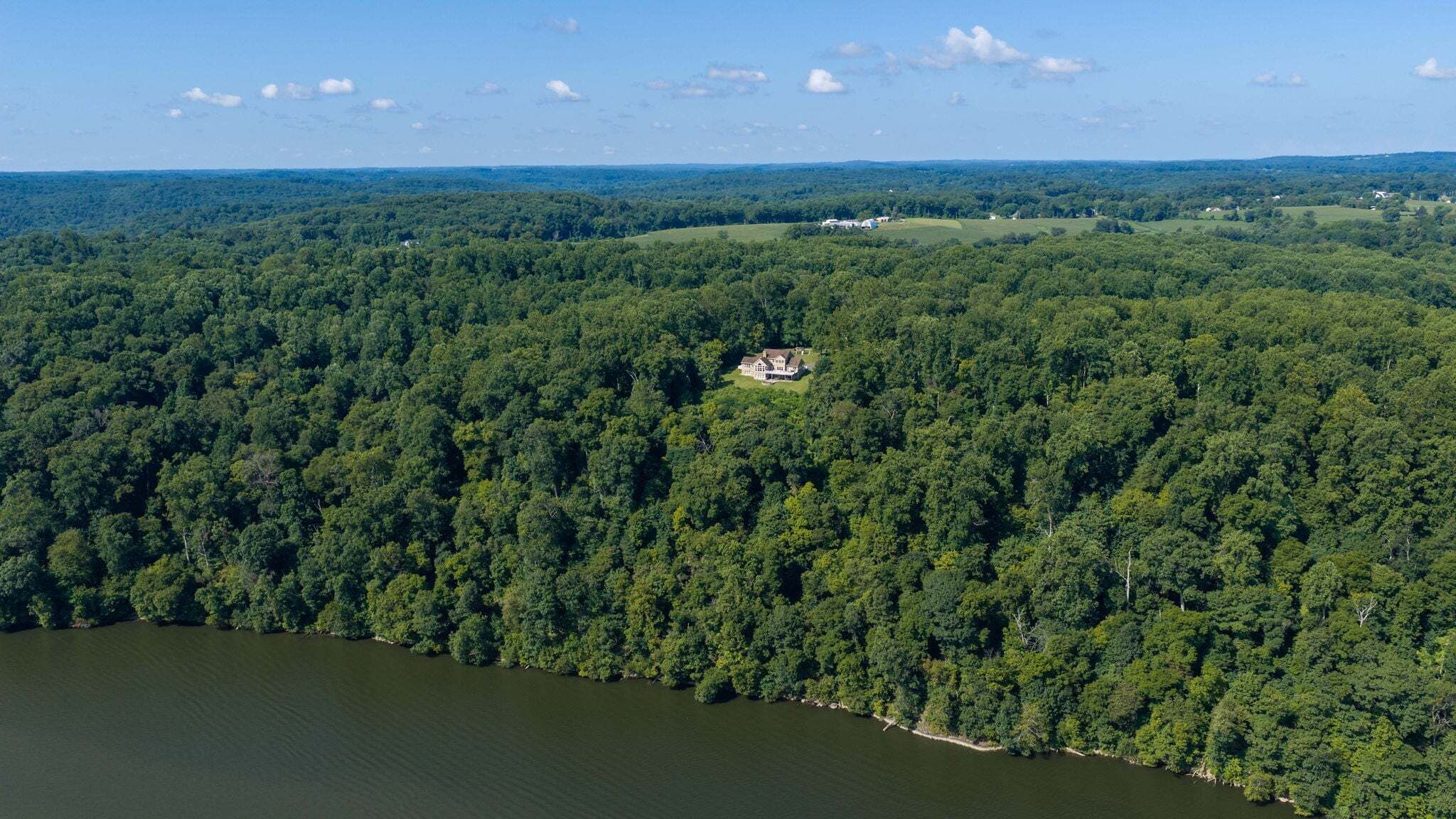 An aerial view of a forested area with a large house surrounded by dense trees.