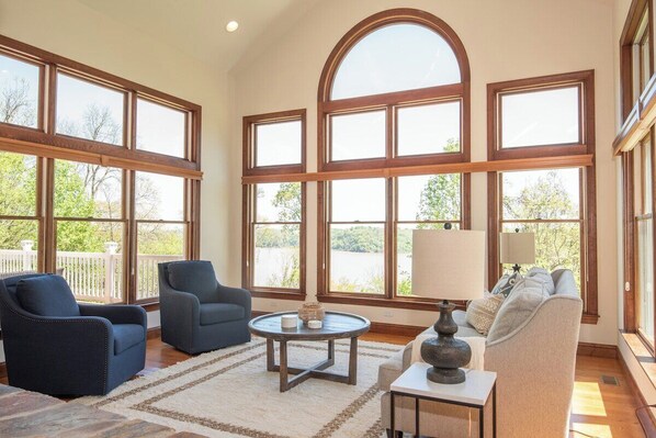 A spacious living room with large windows, a round coffee table, and a sofa.