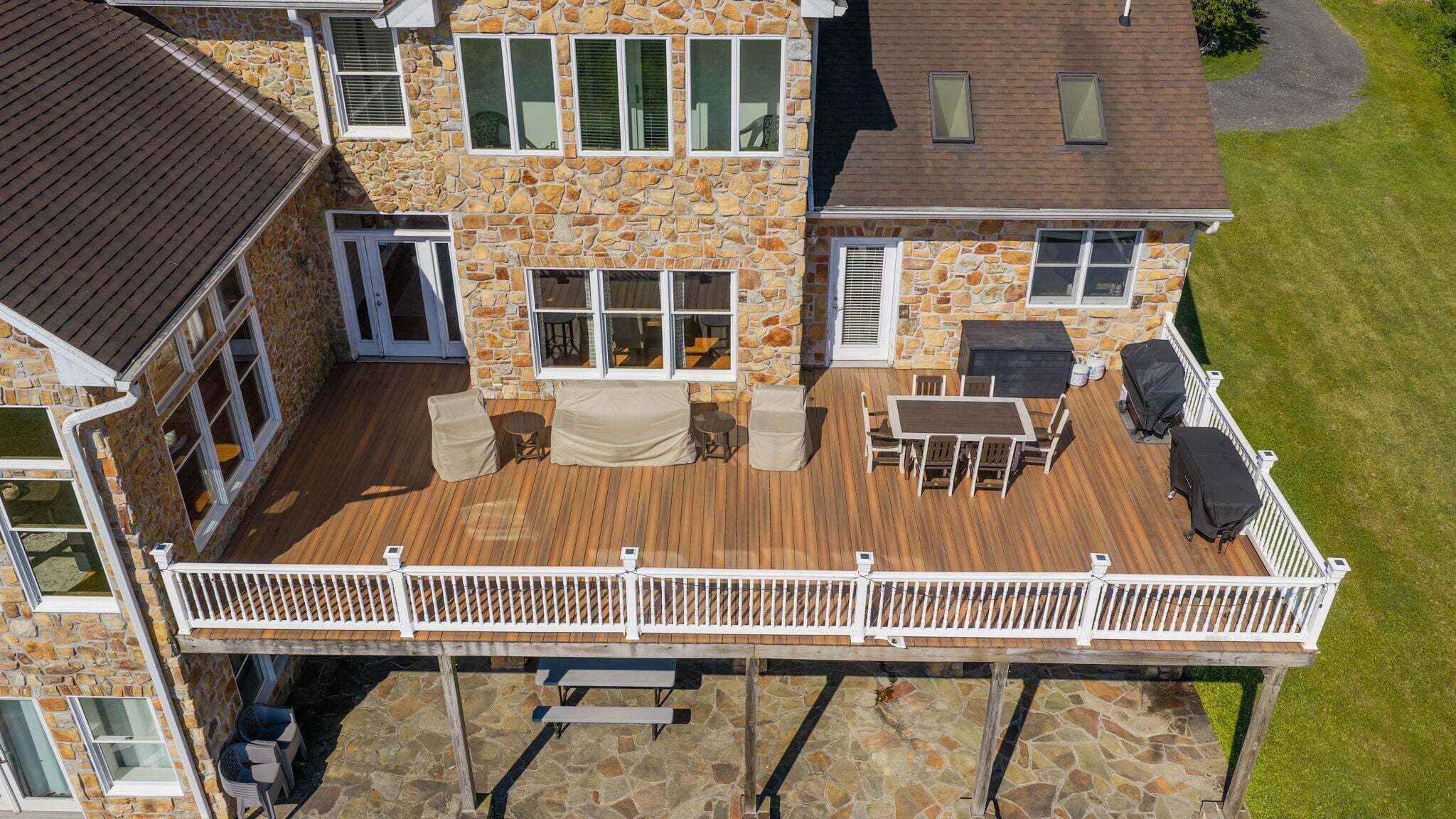 Ein Steinhaus mit einer Holzterrasse, Sitzgelegenheiten im Freien und einer überdachten Veranda.