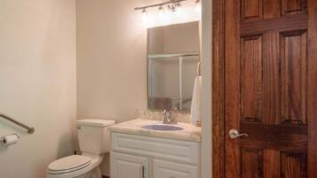 Un baño con inodoro, lavabo, espejo y puerta de madera.
