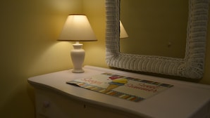 Un comodino con una lampada, uno specchio e un sottopentola decorativo.