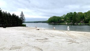 A sandy beach with a lifeguard sign, a calm lake, and a forested area in the background. - Relax at Sunset View in the Hideout Resort (Lake Ariel)