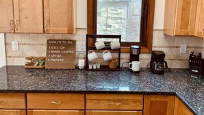 A kitchen with wooden cabinets, a granite countertop, a coffee maker, and a sign with a to-do list. - Relax at Sunset View in the Hideout Resort (Lake Ariel)