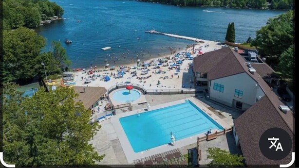 A resort with a swimming pool, beach area, and a view of a lake with boats. - Relax at Sunset View in the Hideout Resort (Lake Ariel)