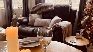 A cozy living room with a leather sofa, a coffee table with candles and a glass, and a Christmas tree. - A beautiful, unique lodge, made for two (Lampeter)