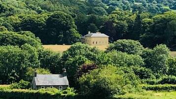 Surrounded by lush greenery and rolling hills, this traditional farmhouse sits peacefully in a serene valley.
