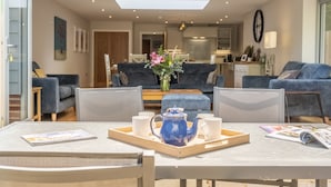 Una sala de estar moderna con comedor, que incluye una tetera azul sobre una bandeja, un sofá y una mesa de centro.