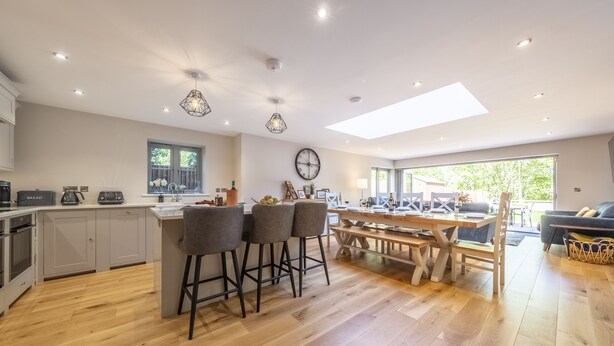 Una cocina moderna con una isla central, taburetes de bar y una mesa de comedor.