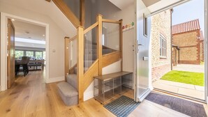 Un interior moderno con una escalera de madera, un comedor y vistas a un edificio de ladrillo.