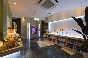 A hotel lobby with a reception desk, a wall-mounted television, and a display of toiletries. - Restay Tina Grace - Adults Only (Hadano)