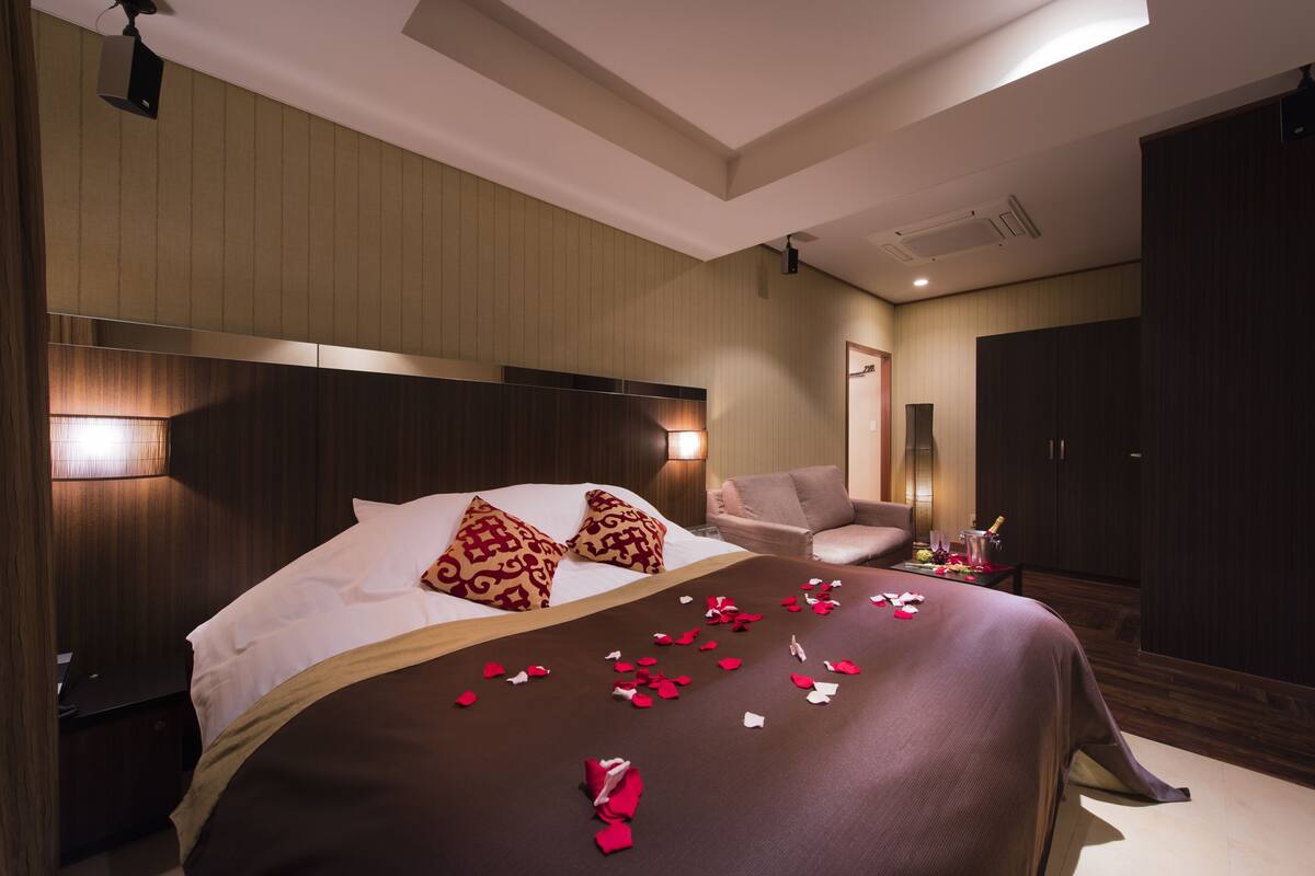 Ein Hotelzimmer mit einem großen Bett, einem Nachttisch, einem Sessel und einem Kleiderschrank.