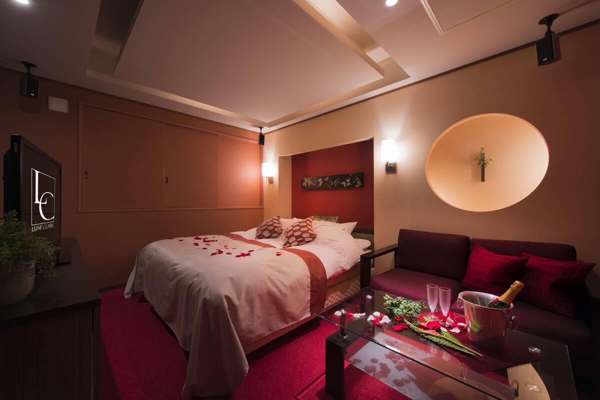 Ein modernes Hotelzimmer mit einem großen Bett, einer Couch, einem Glastisch und einer runden Wandleuchte.