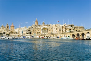 A coastal cityscape with historic buildings, a marina, and a prominent bridge.