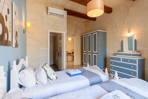 A bedroom with two beds, a wardrobe, and a bathroom visible through an open door.
