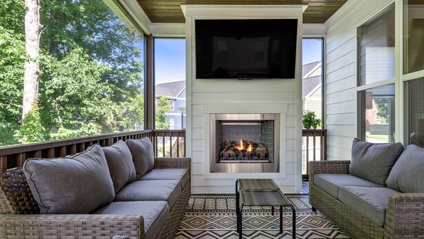 A covered outdoor seating area with a fireplace, wicker furniture, and a patterned rug. - Peaceful Lake Home on TIms Ford (Tullahoma)