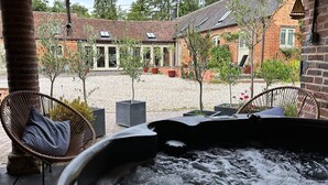 A hot tub area with wicker chairs and a brick building in the background.