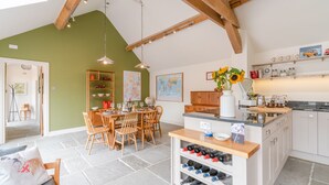 A spacious kitchen with a dining area, wooden beams, a wine rack, and a globe on the wall.