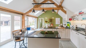 A modern kitchen with a large island, wooden beams, and a view of the outside.