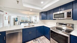 Een moderne keuken met blauwe kastjes, roestvrijstalen apparatuur en een groot kookeiland met een spoelbak.