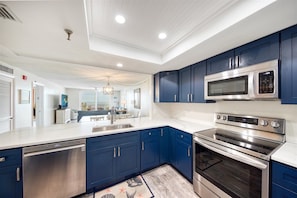 Una cocina moderna con armarios azules, electrodomésticos de acero inoxidable y una isla grande con fregadero.