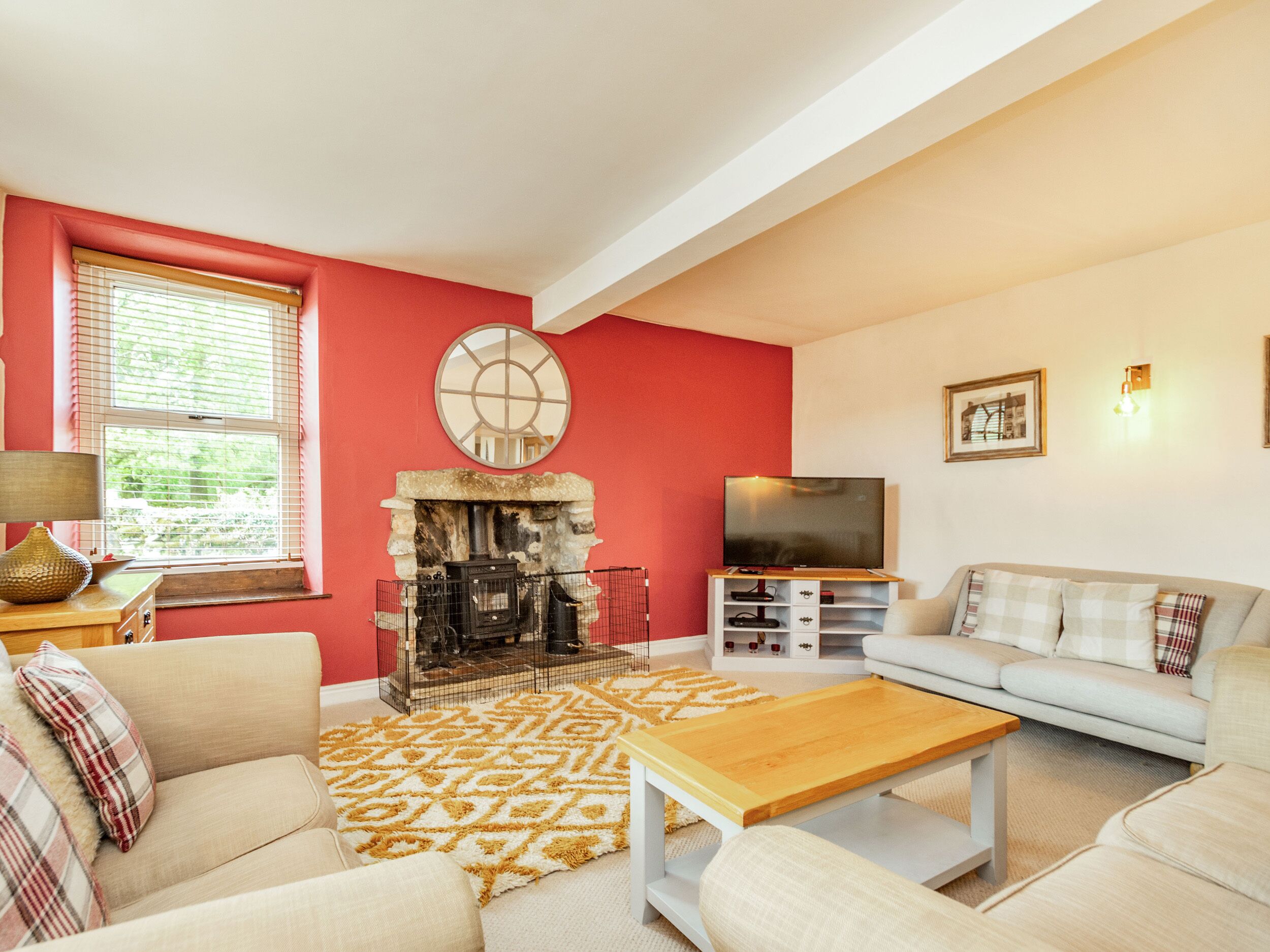 A living room with a fireplace, sofa, television, and a patterned rug.