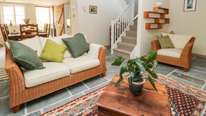 A living room with a sofa, two armchairs, a wooden coffee table, and a staircase. - The Hermitage (Holt)
