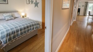 A bedroom with a bed, a nightstand, and wall decorations including a framed picture and two stars. - Apartment 6 (Pwllheli)