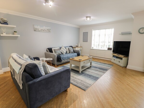 A modern living room with a sofa, a coffee table, and a TV. - Apartment 6 (Pwllheli)