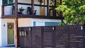 Ein zweistöckiges Haus mit Balkon, grüner Tür und schwarzem Zaun.