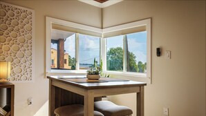 Ein Eckzimmer mit Holztisch und zwei Stühlen, einem Blumentopf und einer Wandverkleidung.