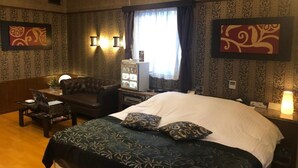 Habitación de hotel con una cama grande, un sofá, un escritorio y una televisión.