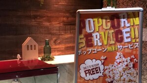 Un letrero publicitando servicio de palomitas de maíz con un mensaje en inglés y japonés.