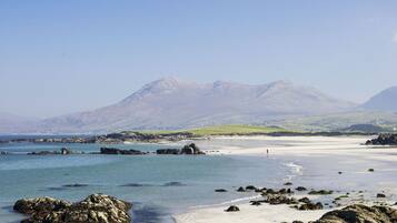 A coastal landscape with rocky shores, clear blue waters, and distant mountains.